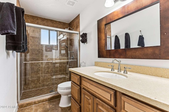 bathroom with toilet, tile patterned flooring, vanity, and a shower with door