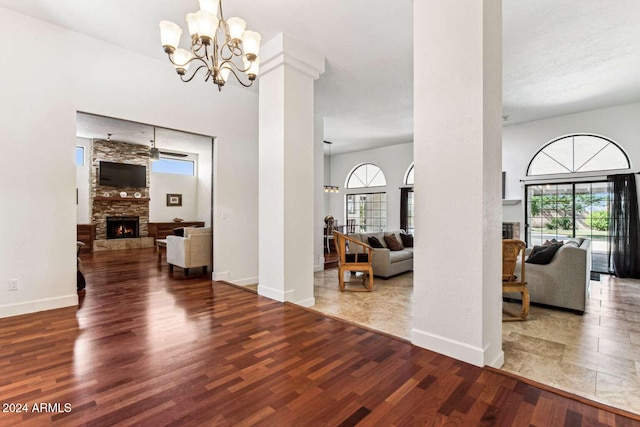 entrance foyer with a stone fireplace, ceiling fan with notable chandelier, and hardwood / wood-style floors