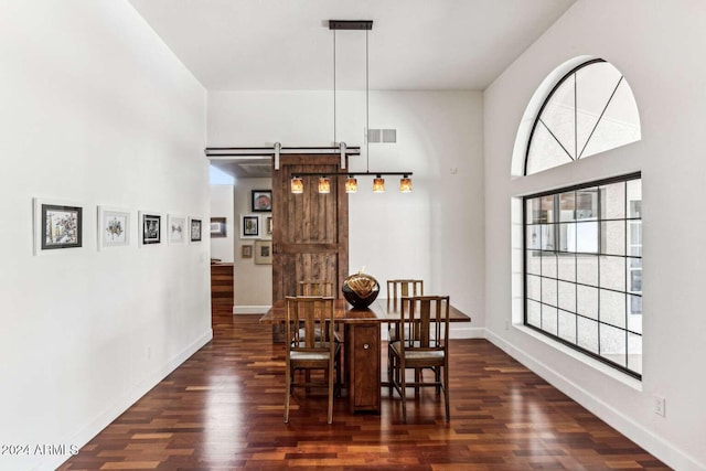 dining room with a barn door and dark hardwood / wood-style flooring