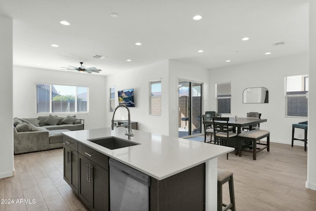 kitchen featuring dishwasher, a kitchen island with sink, sink, ceiling fan, and light hardwood / wood-style floors