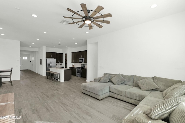 living room with ceiling fan, light hardwood / wood-style flooring, and sink