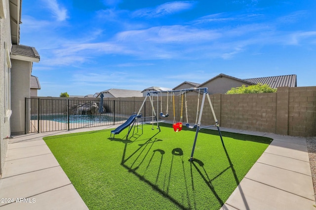 view of play area with a lawn, a fenced in pool, and a patio