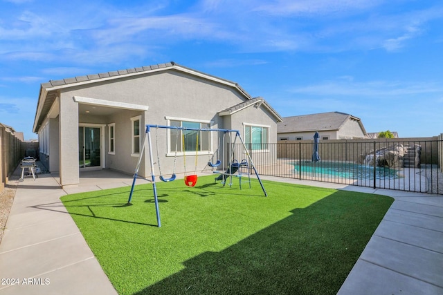 view of playground with a lawn, a patio, and a fenced in pool