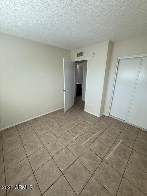 4625 W Thomas Rd Unit 48, Phoenix, AZ 85031 - unfurnished bedroom featuring light tile patterned flooring, a textured ceiling, and a closet