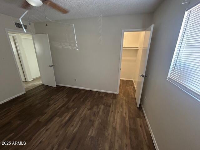 4625 W Thomas Rd Unit 48, Phoenix, AZ 85031 - unfurnished bedroom with dark wood-style flooring, a closet, multiple windows, a walk in closet, and a textured ceiling