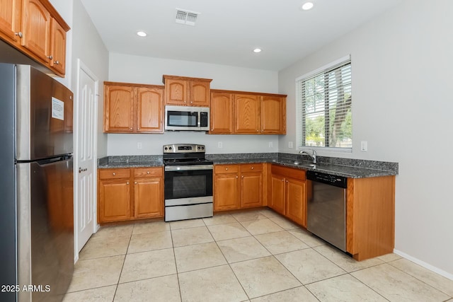 2475 E Vermont Dr, Gilbert, AZ 85295 - kitchen featuring appliances with stainless steel finishes, brown cabinets, dark stone counters, a sink, and recessed lighting