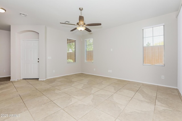 2475 E Vermont Dr, Gilbert, AZ 85295 - empty room with light tile patterned floors, ceiling fan, baseboards, and arched walkways