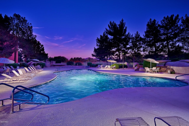 pool at dusk with a patio area