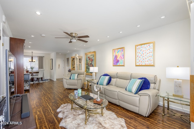 living room featuring dark wood-type flooring and ceiling fan with notable chandelier