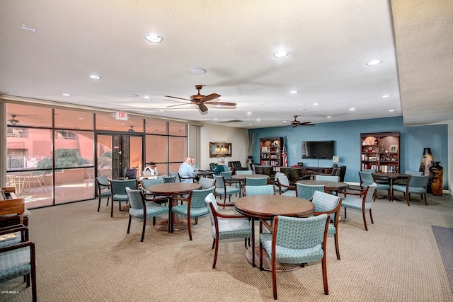 dining space with floor to ceiling windows, light carpet, and ceiling fan