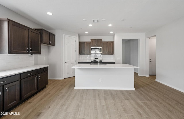 13512 W Copperleaf Ln, Peoria, AZ 85383 - kitchen with stainless steel microwave, tasteful backsplash, recessed lighting, dark brown cabinetry, and light wood finished floors