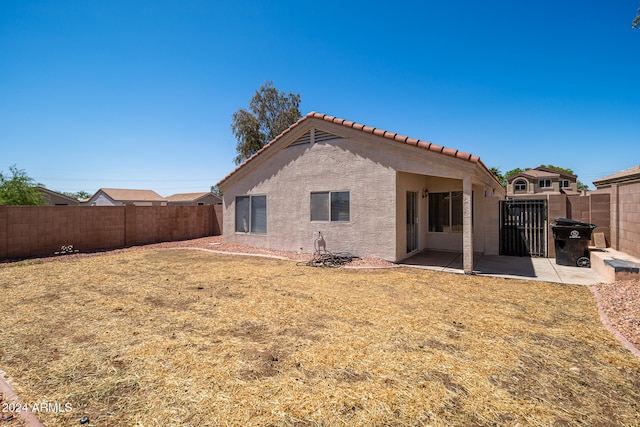 back of property with a yard and a patio