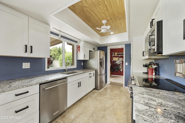 kitchen with white cabinets, a sink, appliances with stainless steel finishes, and a tray ceiling