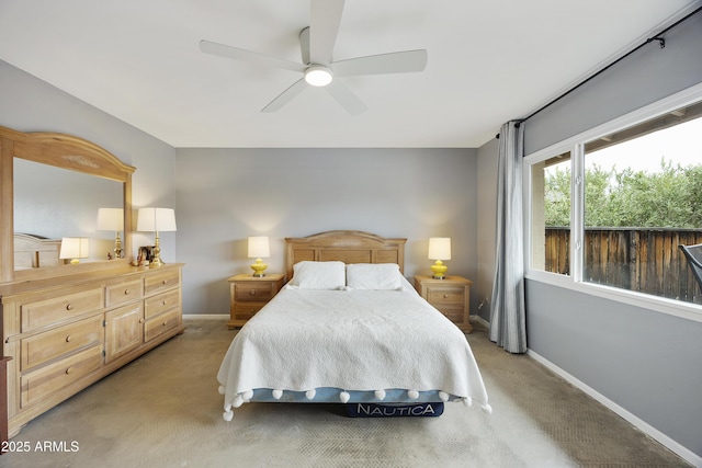 bedroom with light carpet, baseboards, and a ceiling fan