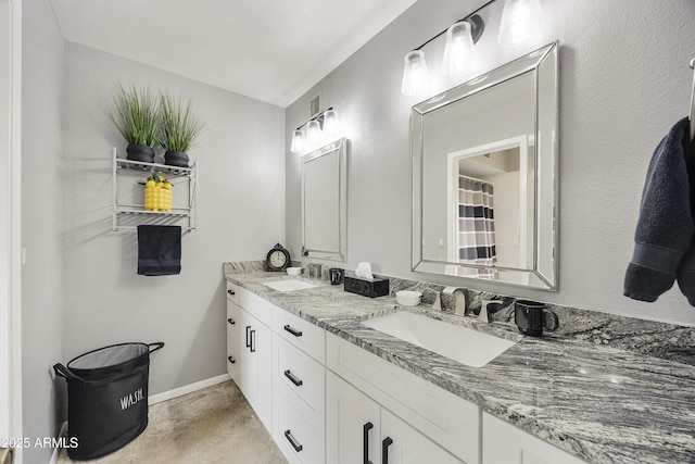 bathroom featuring double vanity, a sink, and baseboards