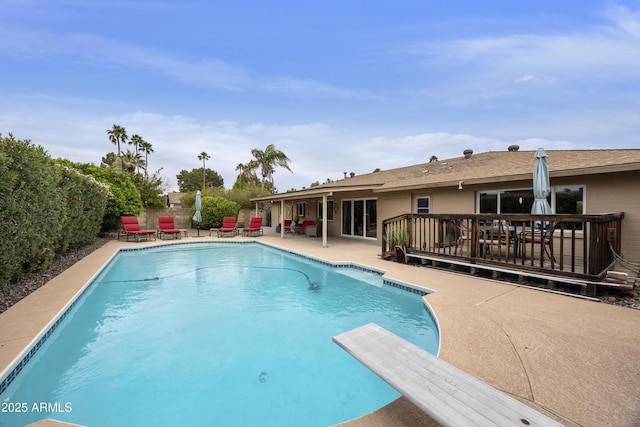 pool with fence, a deck, a patio, and a diving board