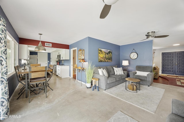 living area featuring a ceiling fan, concrete floors, and visible vents