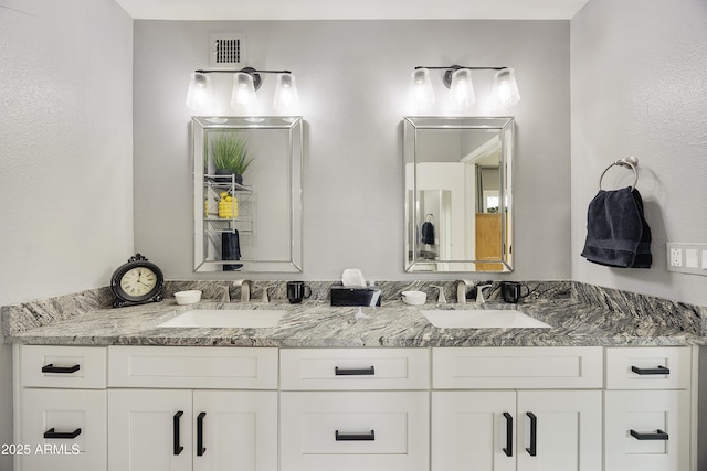 full bath featuring double vanity, visible vents, and a sink