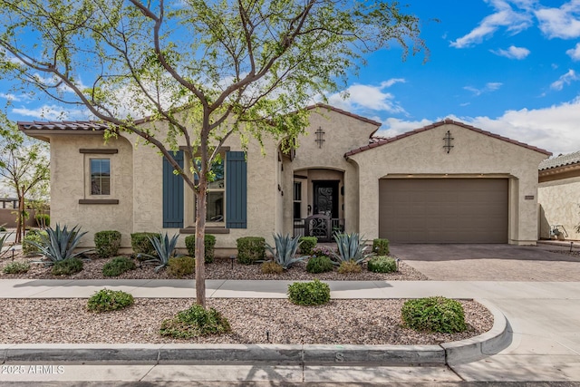mediterranean / spanish-style home with stucco siding, an attached garage, driveway, and a tiled roof