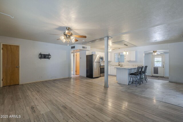 5657 E Dallas St, Mesa, AZ 85205 - unfurnished living room featuring a ceiling fan, light wood-type flooring, a sink, and baseboards