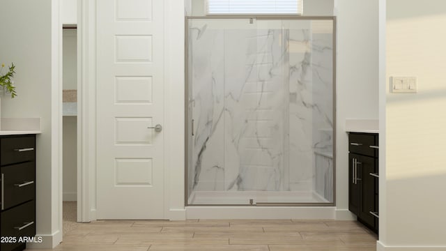 full bathroom featuring vanity, a marble finish shower, and wood finished floors