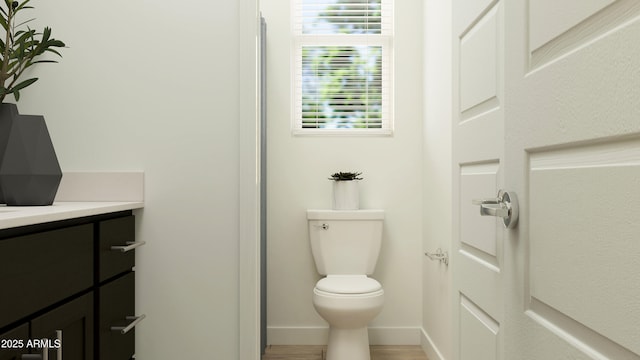 bathroom with vanity, baseboards, wood finished floors, and toilet