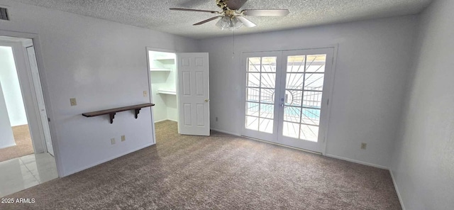 carpeted empty room with ceiling fan, a textured ceiling, and french doors