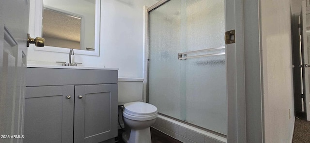 bathroom featuring a textured ceiling, toilet, walk in shower, and vanity