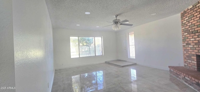 unfurnished room featuring ceiling fan, a brick fireplace, and a textured ceiling