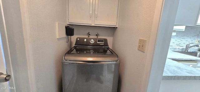 clothes washing area featuring sink, cabinets, and washer / dryer