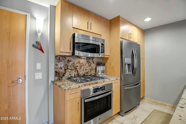 kitchen featuring appliances with stainless steel finishes, light brown cabinets, backsplash, and light stone counters