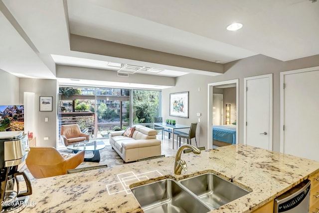 kitchen featuring light stone counters, stainless steel dishwasher, and sink