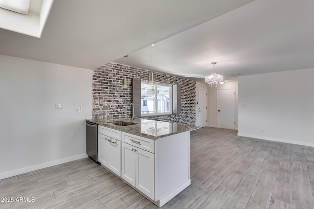 kitchen featuring dark stone countertops, pendant lighting, sink, white cabinetry, and stainless steel dishwasher