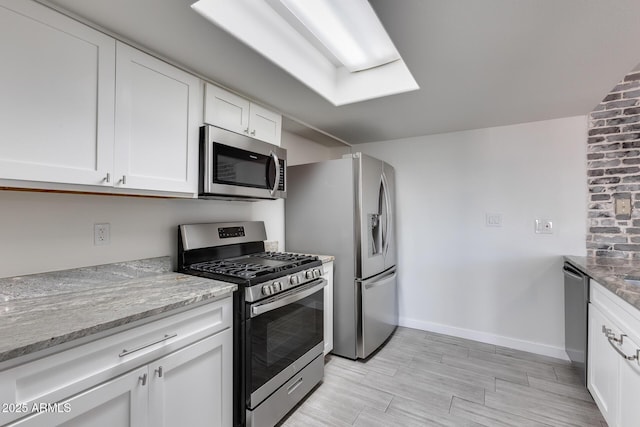 kitchen featuring stainless steel appliances, white cabinets, and light stone counters