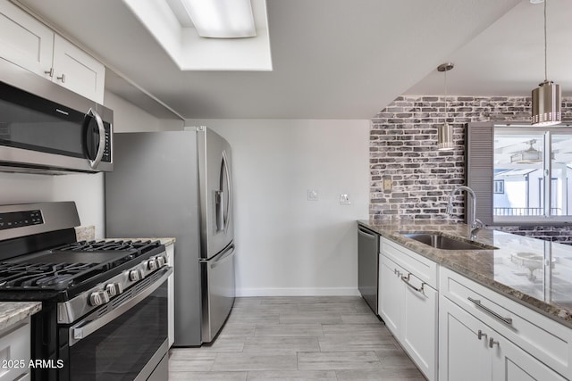 kitchen featuring sink, stainless steel appliances, white cabinetry, and stone countertops