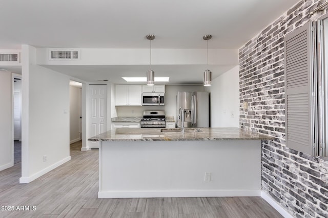 kitchen with stainless steel appliances, hanging light fixtures, light stone countertops, kitchen peninsula, and white cabinetry