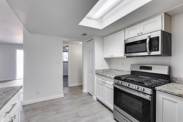 kitchen with light stone countertops, white cabinetry, and appliances with stainless steel finishes