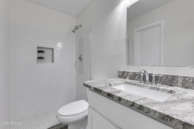 bathroom featuring tiled shower, vanity, and toilet