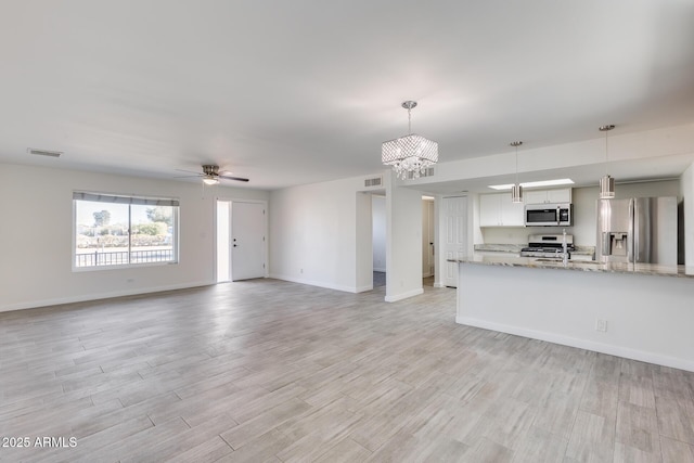 unfurnished living room featuring sink and ceiling fan with notable chandelier