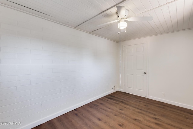 empty room with brick wall, dark hardwood / wood-style flooring, and ceiling fan