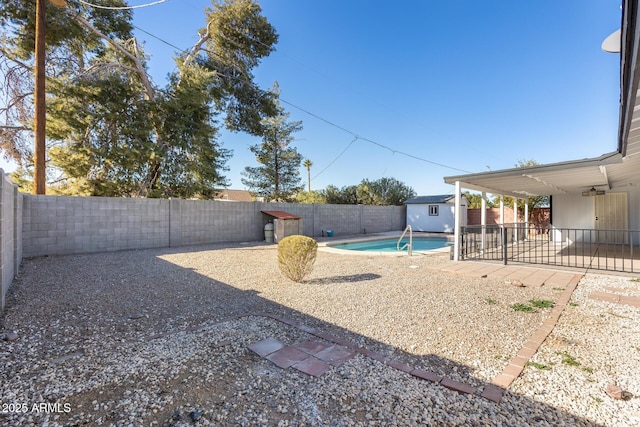 view of yard with ceiling fan, a patio, a fenced in pool, and a storage shed