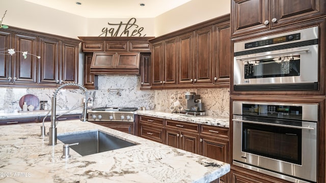 kitchen featuring light stone countertops, sink, oven, and backsplash