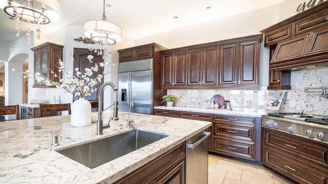 kitchen with sink, decorative backsplash, hanging light fixtures, a notable chandelier, and stainless steel appliances