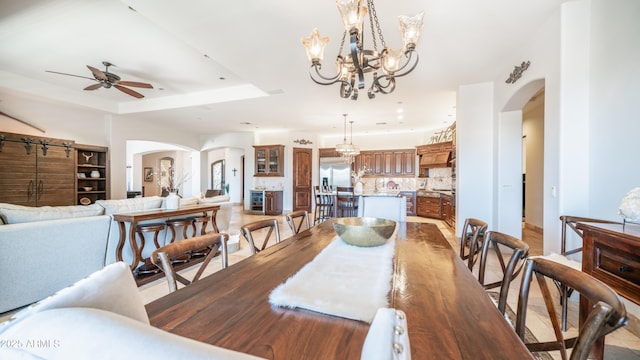 dining space featuring a tray ceiling and ceiling fan with notable chandelier