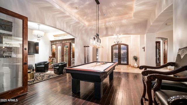 rec room featuring a notable chandelier, a tray ceiling, dark hardwood / wood-style flooring, pool table, and french doors