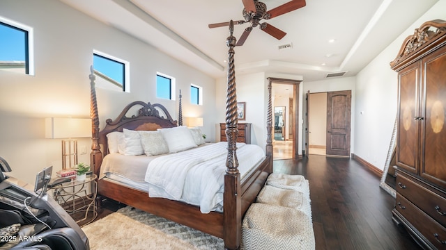 bedroom featuring dark hardwood / wood-style floors, ceiling fan, and a tray ceiling