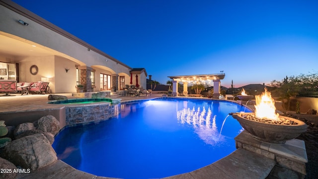 pool at dusk featuring an in ground hot tub, pool water feature, a patio area, and a fire pit