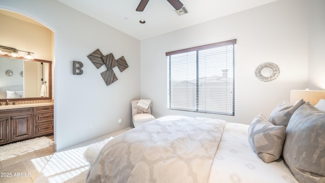 bedroom featuring ceiling fan, ensuite bathroom, and sink