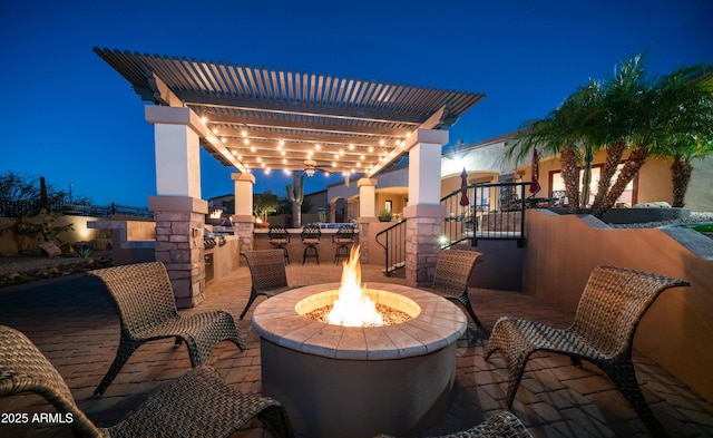 patio at night with an outdoor fire pit and a pergola