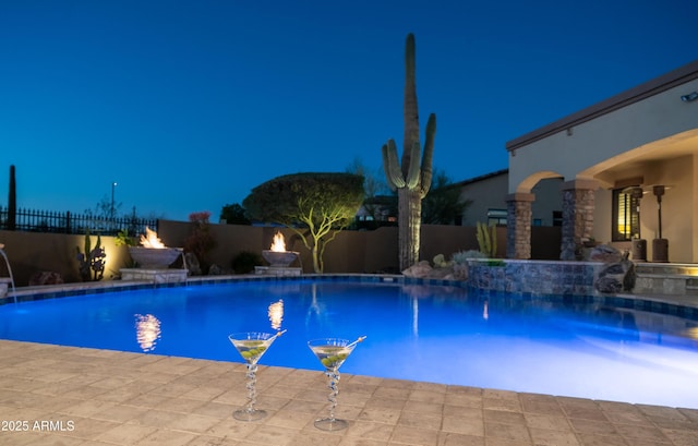 pool at twilight with a patio and pool water feature